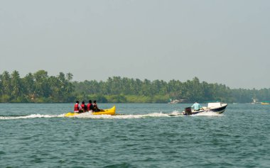 Malvan, INDIA - 23 Aralık 2021: Kimliği belirsiz turist Tarkarli plajında muz gezintisi yapıyor. Kumsal çeşitli su sporları faaliyetleriyle ünlüdür..