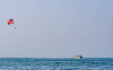 Sindhudurg, INDIA - 23 Aralık 2021: Tarkarli sahilinde paraşütle atlayan kimliği belirsiz turist. Kumsal çeşitli su sporları faaliyetleriyle ünlüdür.