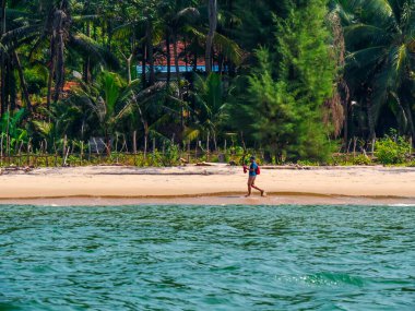 Sindhudurg, Hindistan - 20 Aralık 2021: Sırt çantalı tanımlanamayan bir adam sahilde sabah yürüyüşü yapıyor