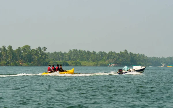 Malvan, INDIA - 23 Aralık 2021: Kimliği belirsiz turist Tarkarli plajında muz gezintisi yapıyor. Kumsal çeşitli su sporları faaliyetleriyle ünlüdür..