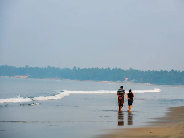 Sindhudurg, Hindistan - 20 Aralık 2021: Tanımlanamayan bir çift sahilde sabah yürüyüşü yapıyor
