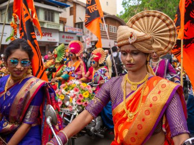 Mumbai, Hindistan - 2 Nisan 2022: Geleneksel giysiler içinde güzel bir Hintli kadın Mumbai 'de Gudhi Padva veya Hindu yeni yılını kutlarken bisiklet sürüyor.