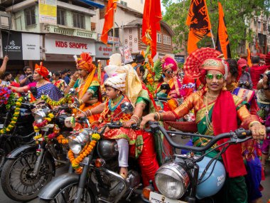 Mumbai, Hindistan - 2 Nisan 2022: Geleneksel giysiler içinde güzel bir Hintli kadın Mumbai 'de Gudhi Padva veya Hindu yeni yılını kutlarken bisiklet sürüyor.