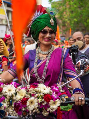 Mumbai, Hindistan - 2 Nisan 2022: Geleneksel giysiler içinde güzel bir Hintli kadın Gudhi Padva veya Hindu Yeni Yıl kutlamaları sırasında bisiklet sürüyor.