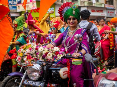 Mumbai, Hindistan - 2 Nisan 2022: Geleneksel giysiler içinde güzel bir Hintli kadın Mumbai 'de Gudhi Padva veya Hindu yeni yılını kutlarken bisiklet sürüyor.