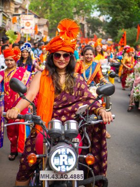 Mumbai, Hindistan - 2 Nisan 2022: Geleneksel giysiler içinde güzel bir Hintli kadın Gudhi Padva veya Hindu Yeni Yıl kutlamaları sırasında bisiklet sürüyor.