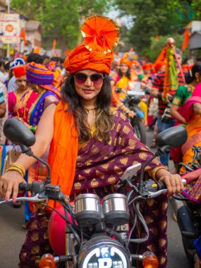 Mumbai, Hindistan - 2 Nisan 2022: Geleneksel giysiler içinde güzel bir Hintli kadın Gudhi Padva veya Hindu Yeni Yıl kutlamaları sırasında bisiklet sürüyor.