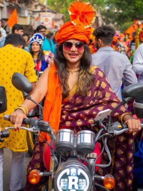 Mumbai, Hindistan - 2 Nisan 2022: Geleneksel giysiler içinde güzel bir Hintli kadın Gudhi Padva veya Hindu Yeni Yıl kutlamaları sırasında bisiklet sürüyor.