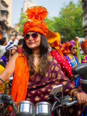 Mumbai, Hindistan - 2 Nisan 2022: Geleneksel giysiler içinde güzel bir Hintli kadın Gudhi Padva veya Hindu Yeni Yıl kutlamaları sırasında bisiklet sürüyor.