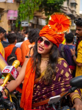 Mumbai, Hindistan - 2 Nisan 2022: Geleneksel giysiler içinde güzel bir Hintli kadın Gudhi Padva veya Hindu Yeni Yıl kutlamaları sırasında bisiklet sürüyor.