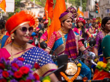 Mumbai, Hindistan - 2 Nisan 2022: Geleneksel giysiler içinde güzel bir Hintli kadın Mumbai 'de Gudhi Padva veya Hindu yeni yılını kutlarken bisiklet sürüyor.