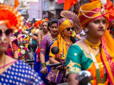 Mumbai, Hindistan - 2 Nisan 2022: Geleneksel giysiler içinde güzel bir Hintli kadın Mumbai 'de Gudhi Padva veya Hindu yeni yılını kutlarken bisiklet sürüyor.