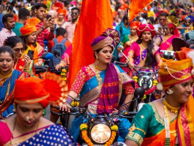 Mumbai, Hindistan - 2 Nisan 2022: Geleneksel giysiler içinde güzel bir Hintli kadın Mumbai 'de Gudhi Padva veya Hindu yeni yılını kutlarken bisiklet sürüyor.