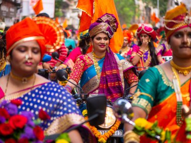 Mumbai, Hindistan - 2 Nisan 2022: Geleneksel giysiler içinde güzel bir Hintli kadın Mumbai 'de Gudhi Padva veya Hindu yeni yılını kutlarken bisiklet sürüyor.