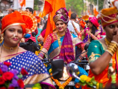 Mumbai, Hindistan - 2 Nisan 2022: Geleneksel giysiler içinde güzel bir Hintli kadın Mumbai 'de Gudhi Padva veya Hindu yeni yılını kutlarken bisiklet sürüyor.