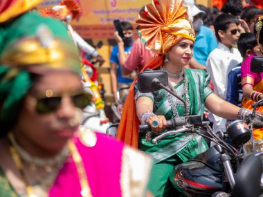 Mumbai, Hindistan - 2 Nisan 2022: Geleneksel giysiler içinde güzel bir Hintli kadın Mumbai 'de Gudhi Padva veya Hindu yeni yılını kutlarken bisiklet sürüyor.