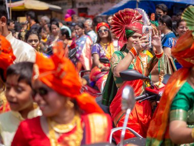 Mumbai, Hindistan - 2 Nisan 2022: Geleneksel giysiler içinde güzel bir Hintli kadın Mumbai 'de Gudhi Padva veya Hindu yeni yılını kutlarken bisiklet sürüyor.