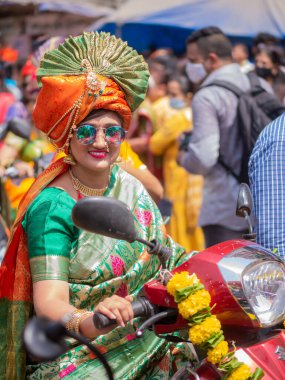 Mumbai, Hindistan - 2 Nisan 2022: Geleneksel giysiler içinde güzel bir Hintli kadın Mumbai 'de Gudhi Padva veya Hindu yeni yılını kutlarken bisiklet sürüyor.