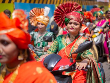 Mumbai, Hindistan - 2 Nisan 2022: Geleneksel giysiler içinde güzel bir Hintli kadın Mumbai 'de Gudhi Padva veya Hindu yeni yılını kutlarken bisiklet sürüyor.