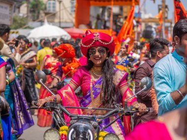 Mumbai, Hindistan - 2 Nisan 2022: Geleneksel giysiler içinde güzel bir Hintli kadın Mumbai 'de Gudhi Padva veya Hindu yeni yılını kutlarken bisiklet sürüyor.