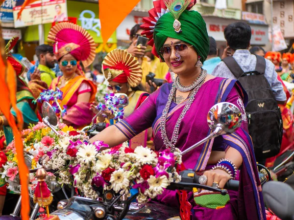 Mumbai, Hindistan - 2 Nisan 2022: Geleneksel giysiler içinde güzel bir Hintli kadın Mumbai 'de Gudhi Padva veya Hindu yeni yılını kutlarken bisiklet sürüyor.