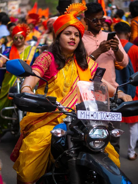 Mumbai, Hindistan - 2 Nisan 2022: Geleneksel giysiler içinde güzel bir Hintli kadın Gudhi Padva veya Hindu Yeni Yıl kutlamaları sırasında bisiklet sürüyor.