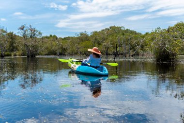 Asyalı bir kadın tatillerde doğayı görmek için nehirde kayak yapıyor..