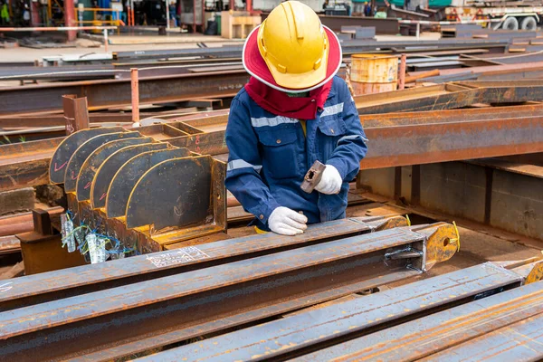 Workers use a hammer to stamp characters and numbers with steel hand stamps on steel structure beams for identification workpieces.