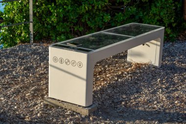 Smart Solar Bench in public place,  powered by sunlight provides wireless and wired charging for users, free wifi and temperature and weather sensors.