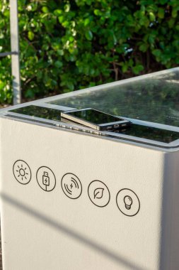 Smart Solar Bench in public place,  powered by sunlight provides wireless and wired charging for users, free wifi and temperature and weather sensors.