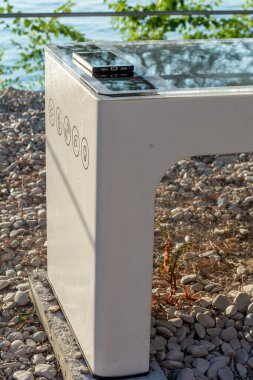 Smart Solar Bench in public place,  powered by sunlight provides wireless and wired charging for users, free wifi and temperature and weather sensors.