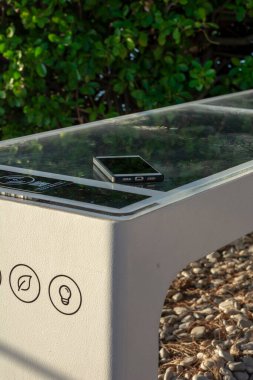 Smart Solar Bench in public place,  powered by sunlight provides wireless and wired charging for users, free wifi and temperature and weather sensors.