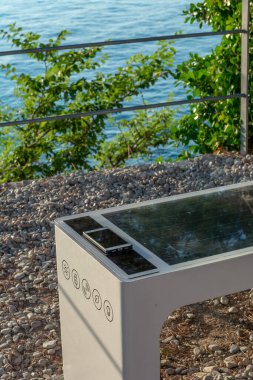 Smart Solar Bench in public place,  powered by sunlight provides wireless and wired charging for users, free wifi and temperature and weather sensors.