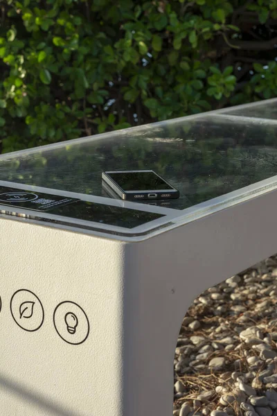 Smart Solar Bench in public place,  powered by sunlight provides wireless and wired charging for users, free wifi and temperature and weather sensors.