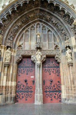 Taş bir duvarda siyah demir süslemeleri olan kemerli ahşap bir kapı. Hronsky Benadik köyündeki Saint Benedict Bazilikası. Slovakya.