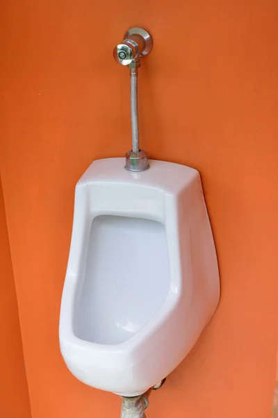 Einzelurinal an orangefarbener Wand in öffentlicher Toilette — Stockfoto