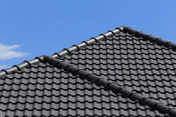 Techo de azulejos negros en una nueva casa con cielo azul — Foto de Stock