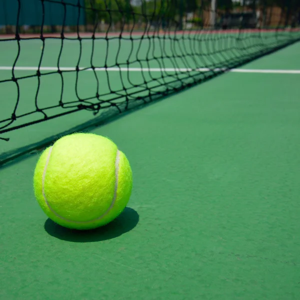 Теннисный мяч на зеленой старой площадке — стоковое фото