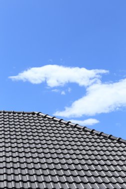 Mavi gökyüzü ile yeni bir ev üzerinde siyah kiremit çatı