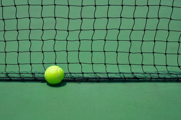 Тенісний м'яч на зеленому старому дворі — стокове фото