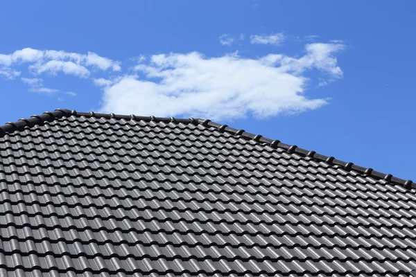 Zwarte tegels dak op een nieuw huis met blauwe hemel — Stockfoto