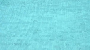 Yavaş çekim, berrak su dalgalanması mavi yüzme havuzunda beyaz fayanslı zemin