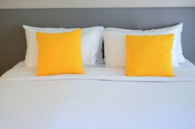 Beyaz yatakta sarı yastık, iç tasarım.