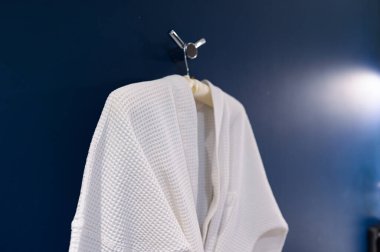 Bornoz koyu mavi duvarda asılı.