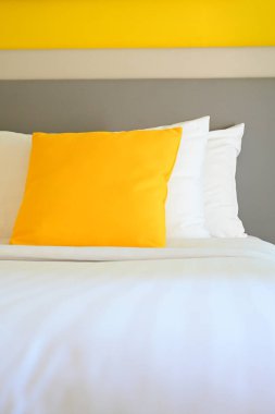 Beyaz yatakta sarı yastık, iç tasarım.