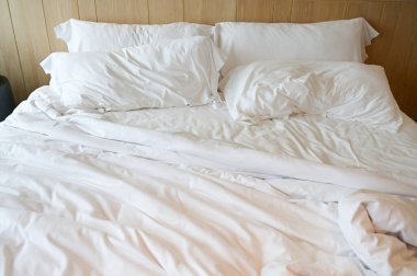 Beyaz yatak ve yastıklar odada.