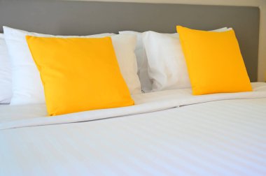 Beyaz yatakta sarı yastık, iç tasarım.