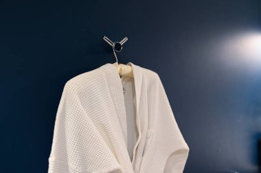 Bornoz koyu mavi duvarda asılı.