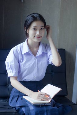 Asya Taylandlı lise öğrencisi üniforması. Güzel kız bir kitap okumuş.