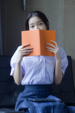 Asya Taylandlı lise öğrencisi üniforması. Güzel kız bir kitap okumuş.